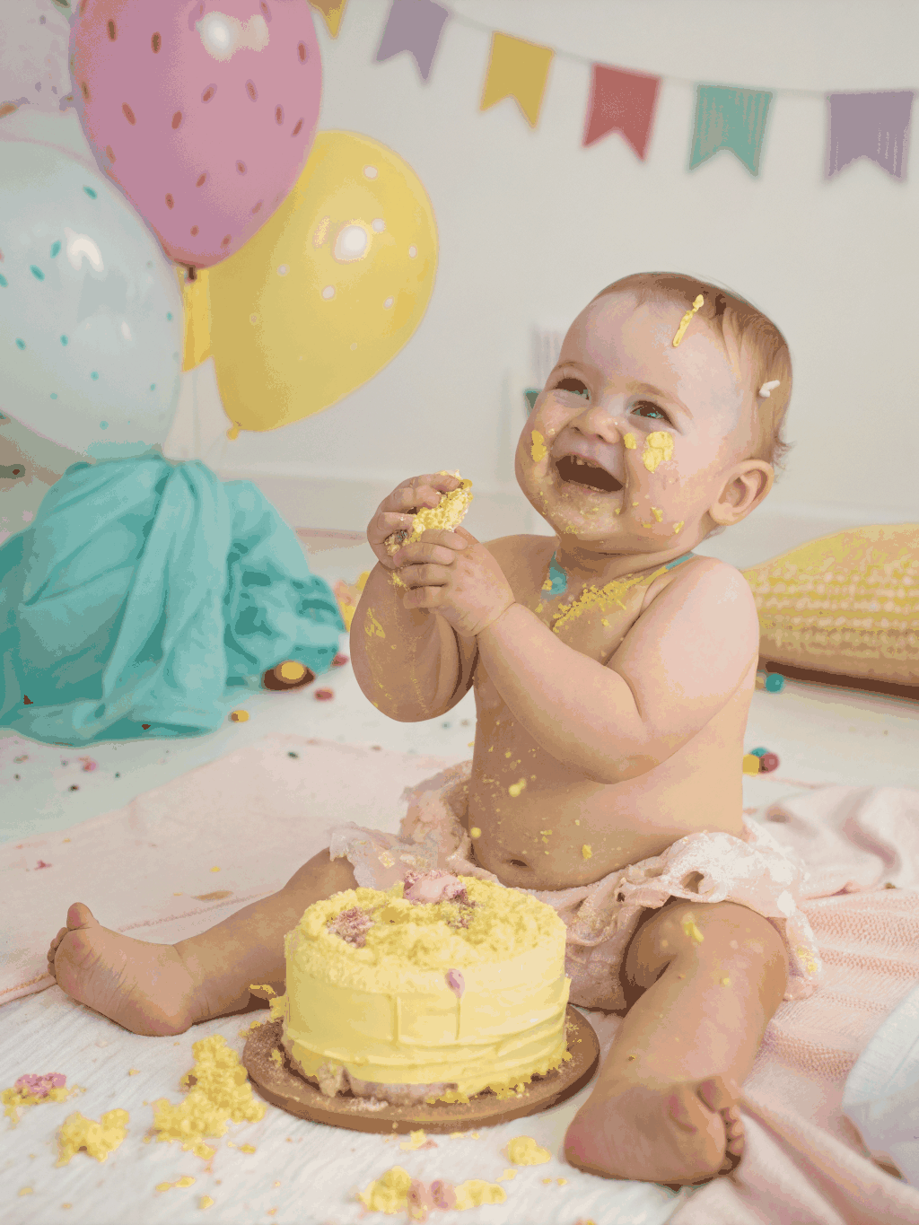 Toddler smashing colorful birthday cake with family laughing